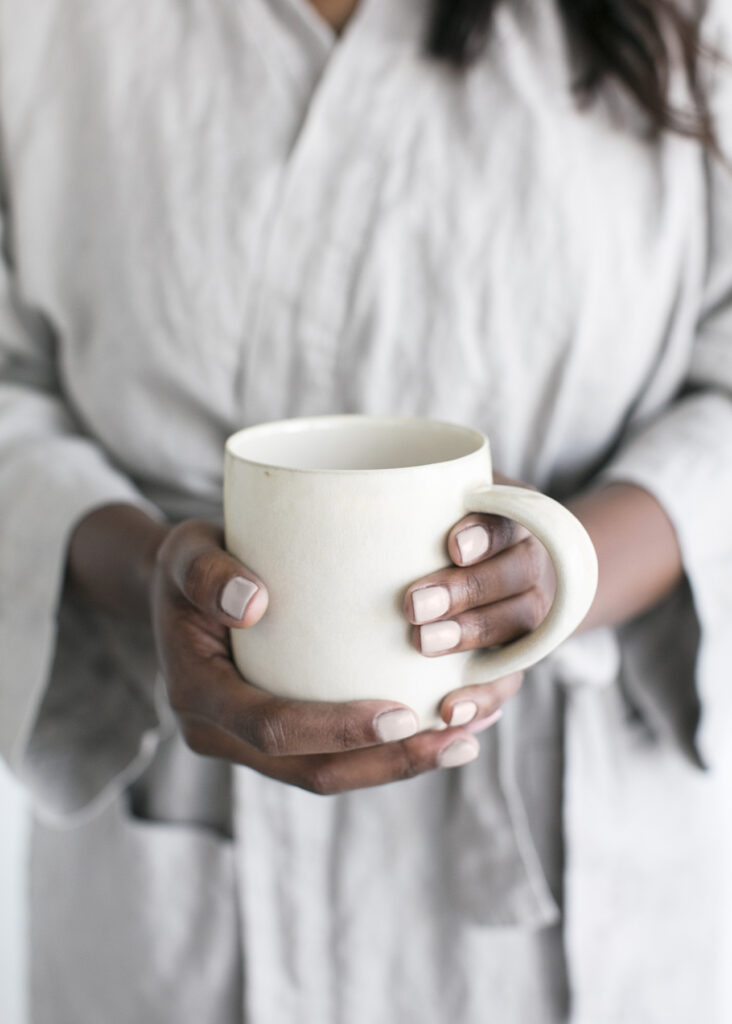 An image of a woman holding a cup on a blog about creating a holistic postpartum mom-care plan.